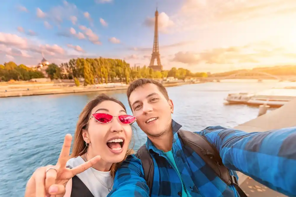 Happy couple taking selfie in Paris with Eiffel Tower in background