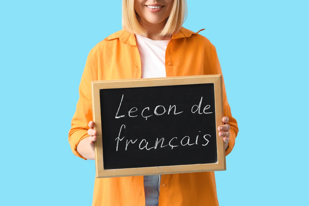 Woman holding a chalkboard that says "Leçon de français